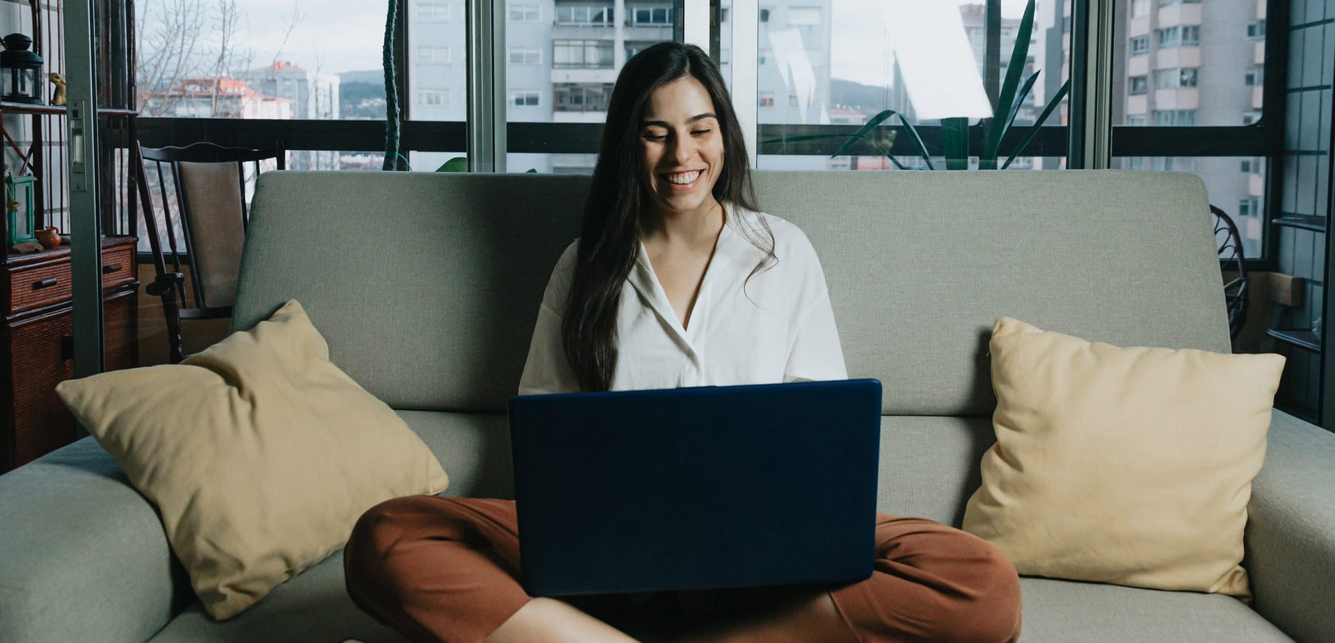 woman-sits-on-a-couch-while-looking-at-laptopAdjusted